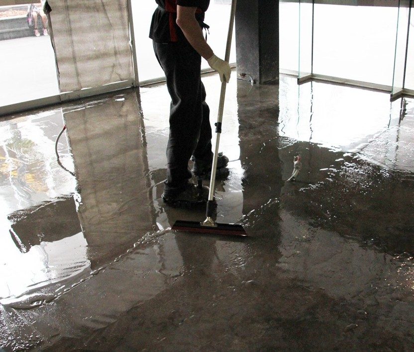 A installer squeegeeing out a clear epoxy, showing the darkening effect and how difficult it can be to spot misses.
