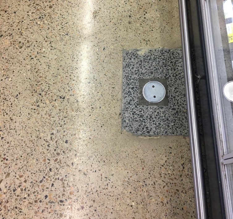 A patch in a polished concrete floor that's highly visible due to mismatching concrete mix.