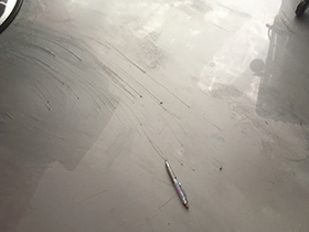 A pen sitting on top of an epoxy floor to give scale to the defects created by the metallic pigment.