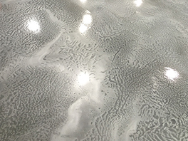 A metallic floor with defects resembling tiger stripes that have ruined the finish.