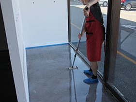An installer using a pole sander to smooth out small protrusions on the basecoat of a decorative flooring system.