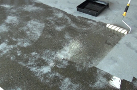 A sealer being applied by roller onto a very porous concrete slab.