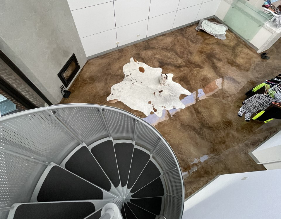 A picture taken from above a residential living room that used a clear epoxy resin to create a rustic coloured concrete finish.