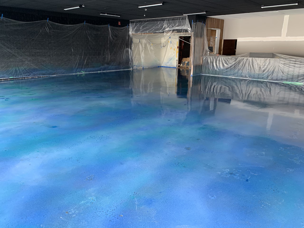 An empty commercial space with a new, deep blue metallic decorative floor waiting to be fitted out.