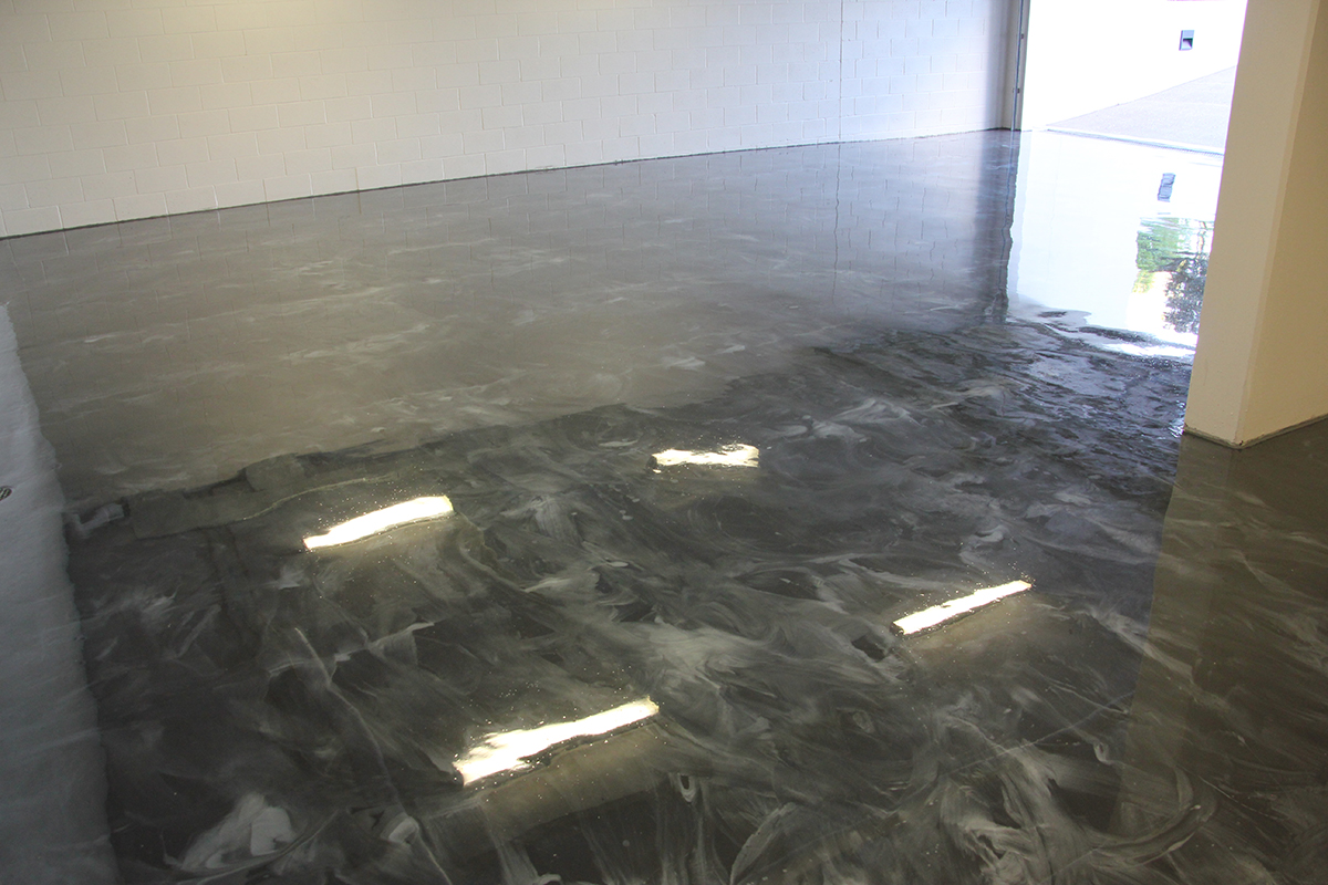A photo taken from the back of a large residential garage with a new epoxy decorative floor installed.