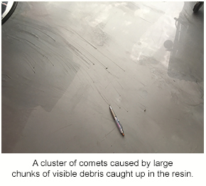 A cluster of comets on a decorative floor caused by large chunks of debris getting caught in the resin.