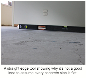 A straight edge tool lying across a concrete slab to show how not all surfaces are flat when it comes to decorative floors.