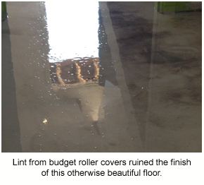 A low-angle photo of a glossy epoxy floor showing lint from the roller cover stuck in the film.