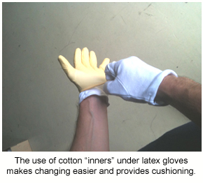 An installer putting on latex gloves over the top of white cotton gloves.