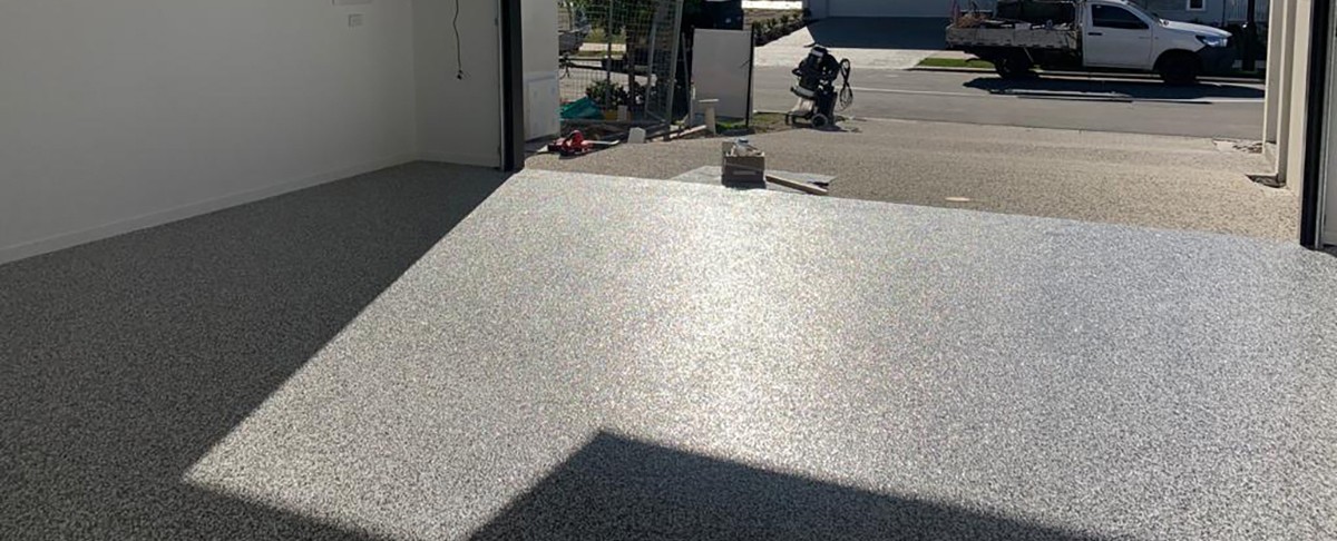 A photo from the back of an open garage showing the beautiful, even finish of the fast flake flooring system from Real World Epoxies.