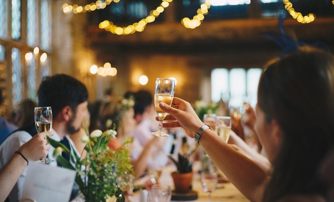 People around a dinner table toasting to success of a friend's business.