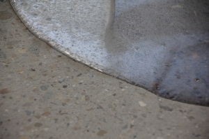 A concrete coating puddle on top of a concrete floor.
