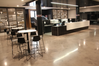 The decorative epoxy floor in the Adelaide Oval club room with tables and chairs and a central bar area.