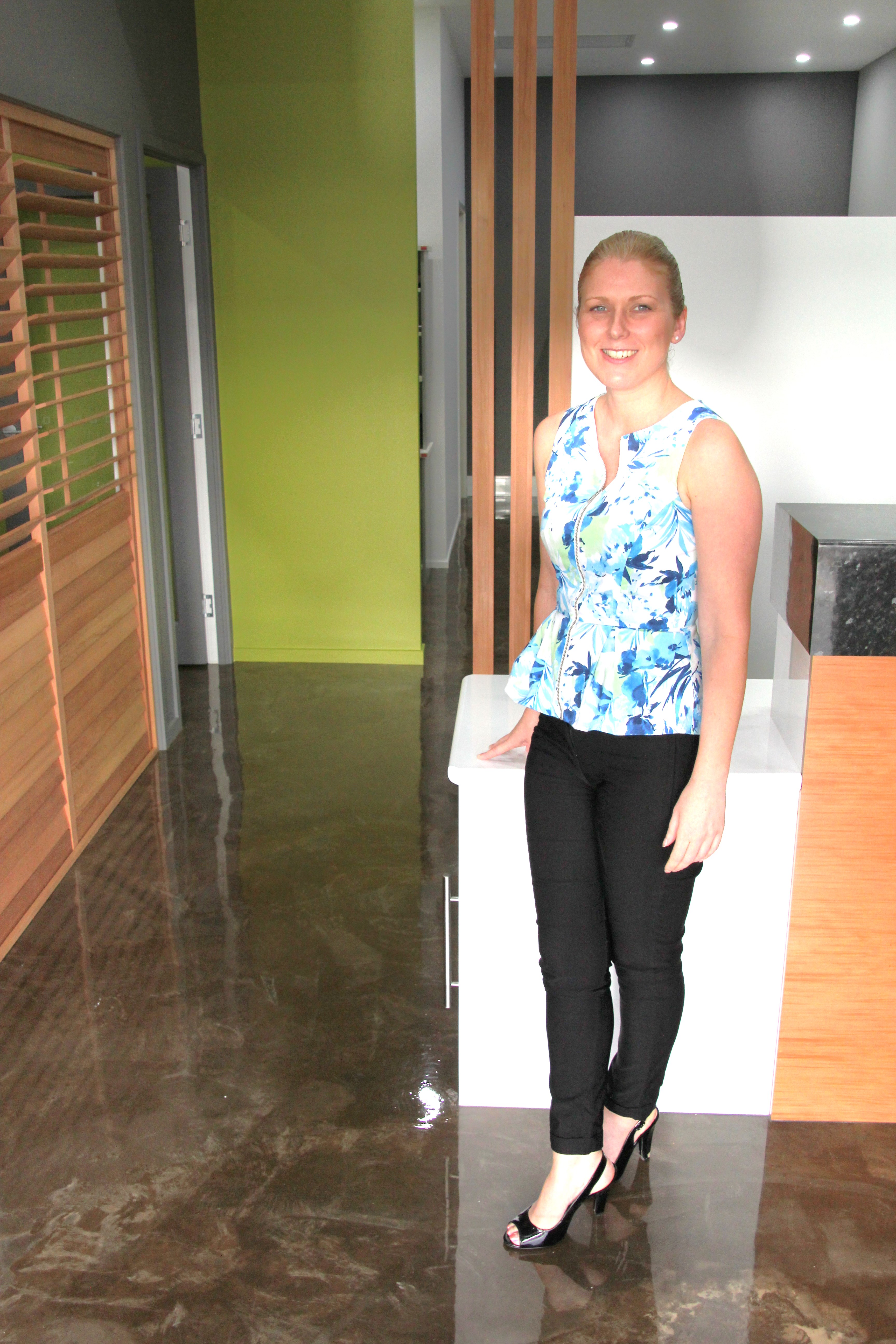 A smiling real estate agent standing on the decorative epoxy floor near the front of the office.