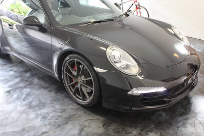 A black Porsche parked on top of the silver metallic epoxy floor.