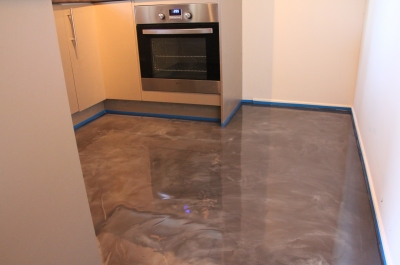 A photo of the entrance to the kitchen taken at bench height, with oven, cabinets and new metallic epoxy floor visible.