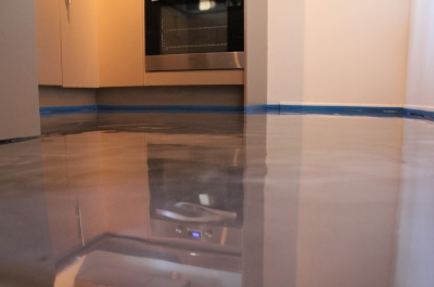 A low-angle shot of the metallic epoxy floor taken at the entrance to the kitchen that highlights the glossy finish.