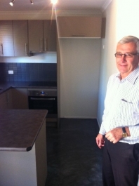 The smiling kitchen owner standing in front of the kitchen with new metallic epoxy floor installed.