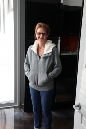 The smiling homeowner standing on the stunning metallic epoxy floor at the end of the project.