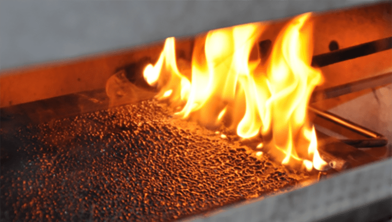 A photo of flames burning a test sample in the specialist equipment used to perform the fire tests.