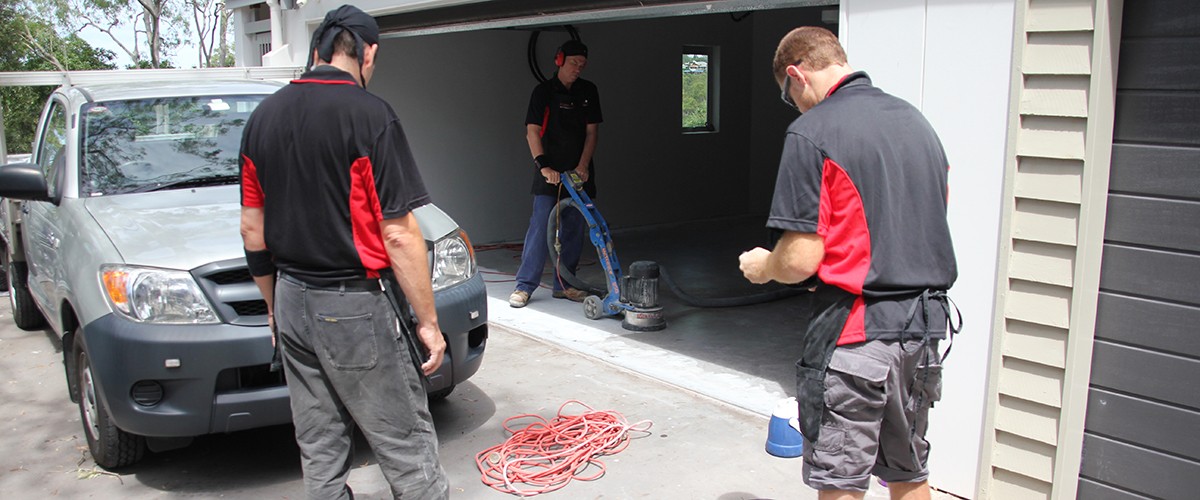 A team of resin flooring installers planning the surface preparation stage of a garage flooring project.