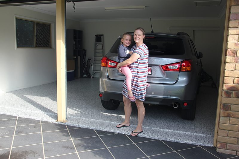 A happy homeowner and her daughter posing on the new epoxy flooring in their garage.