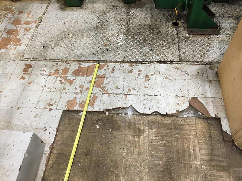 A messy and damaged floor in the middle of tile removal.