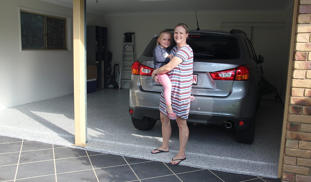 A smiling homeowner and her daughter standing on their new garage epoxy floor.