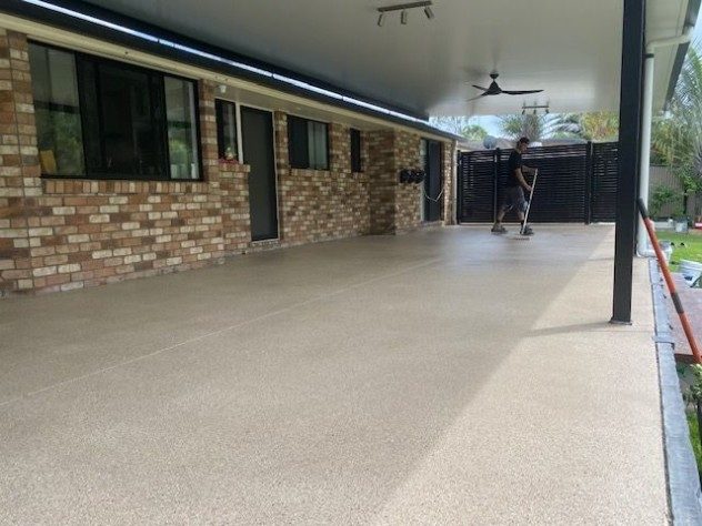 Resin Granite flake flooring on a patio with the installer in the process of applying the clear topcoat.