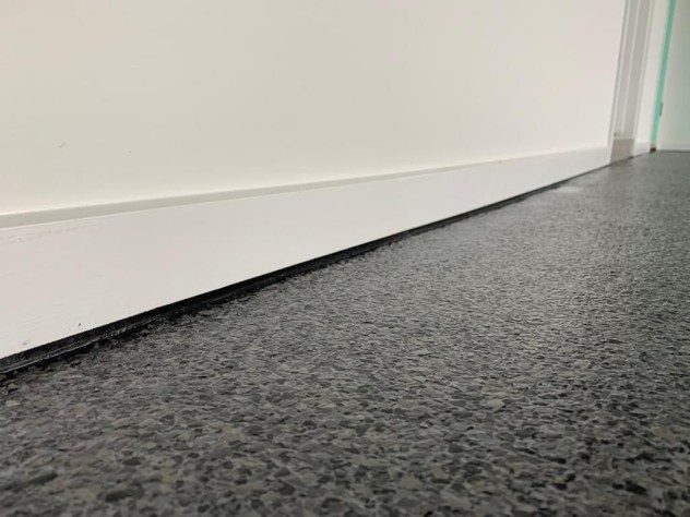 A close up, low-angle shot of the floor-wall junction in a garage showing the Resin Vinyl finish.
