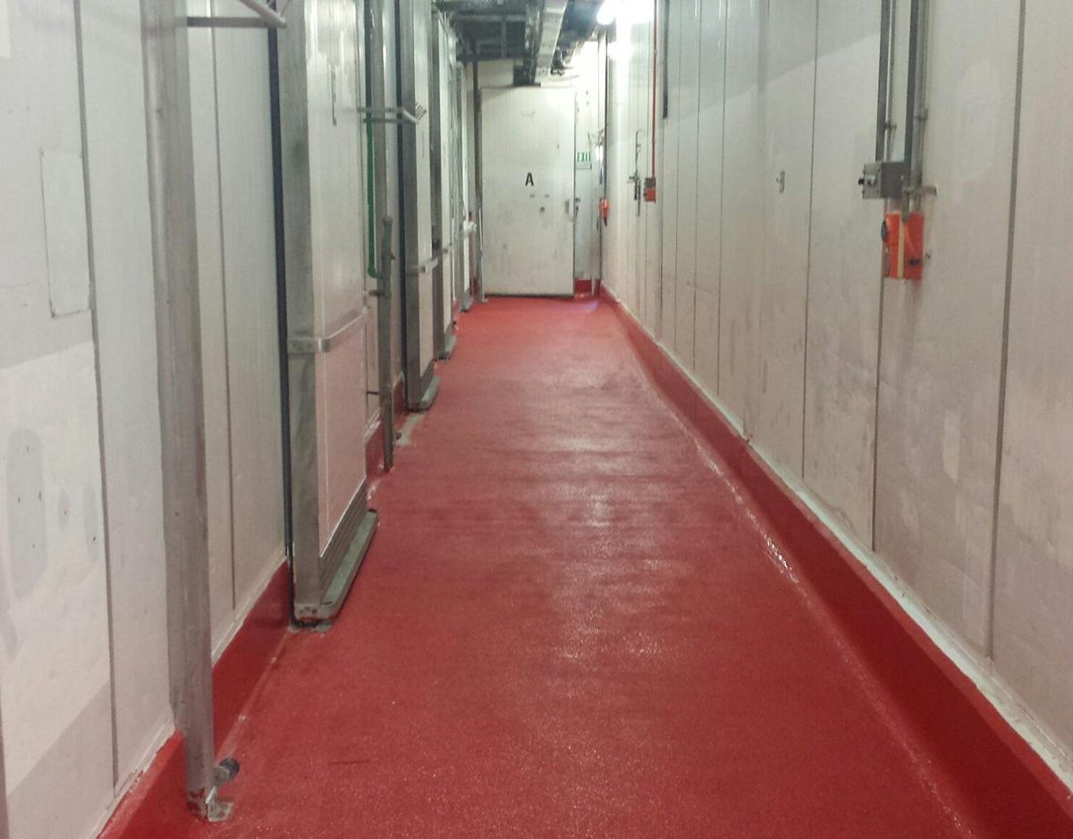 A hallway in an abattoir that used Jaxxon coatings to provide a durable, non-slip flooring surface in a signal red colour.