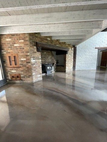 A custom floor with Ezypoly topcoat in a residential living area containing a rustic looking fire place and brick wall facade.