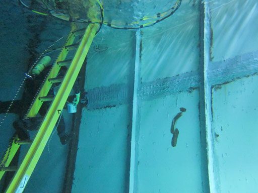 A diver peforming underwater leak repairs on the seams of a large drinking water tank.