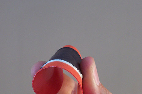 A patch of nylon with Scubapoxy adhesive being squeezed together by a hand to show flexibility.