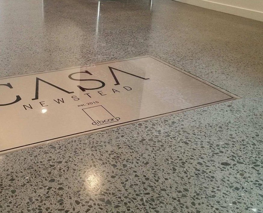 A beautiful polished concrete floor with corporate logo in the foyer of a city office.