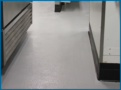 Seamless commercial epoxy flooring running throughout a commercial kitchen.
