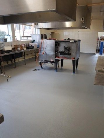 A large cooking appliance being installed in a commercial kitchen that has a Resin Grip system applied.