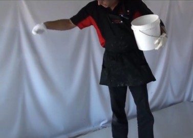 An installer standing on the epoxy basecoat, tossing the non-slip particle from a bucket onto the wet film.