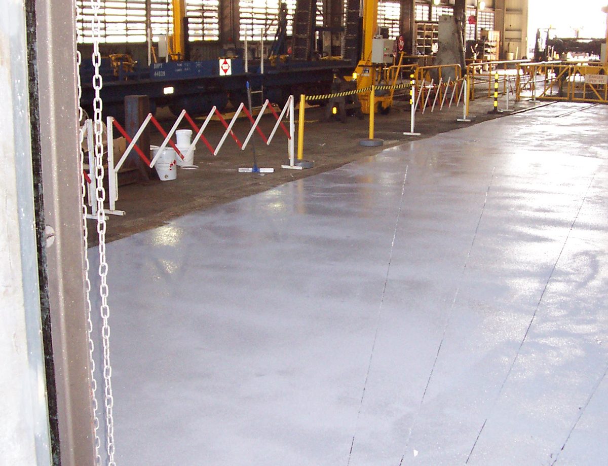 A photo taken at the completion of the project showing the new non-slip floor protected by barriers in the workshop area.