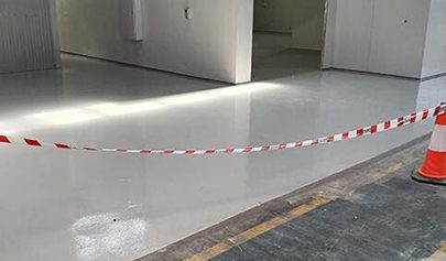 A photo of tape being used to keep people off a freshly applied Resin Grip system in a factory.