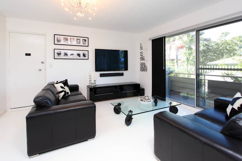 A white epoxy floor in the living area and lounge room of a suburban apartment.