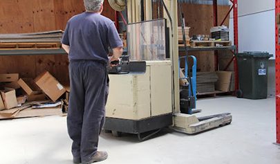 A walk-behind forklift being used on a light grey Resin Guard floor in a manufacturing factory.