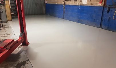 The Resin Guard system immediately after being applied to the concrete in a small car workshop that has had all the equipment removed.