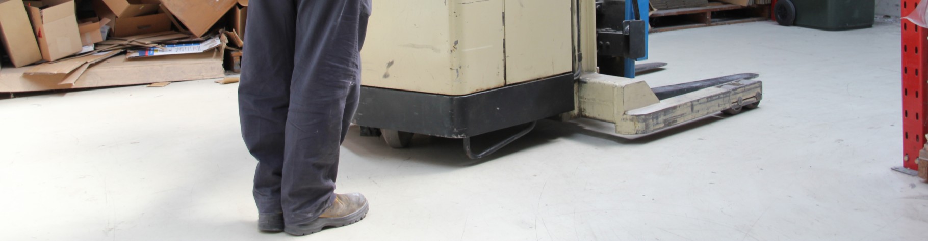 A walk-behind electric forklift being used on a warehouse epoxy floor.