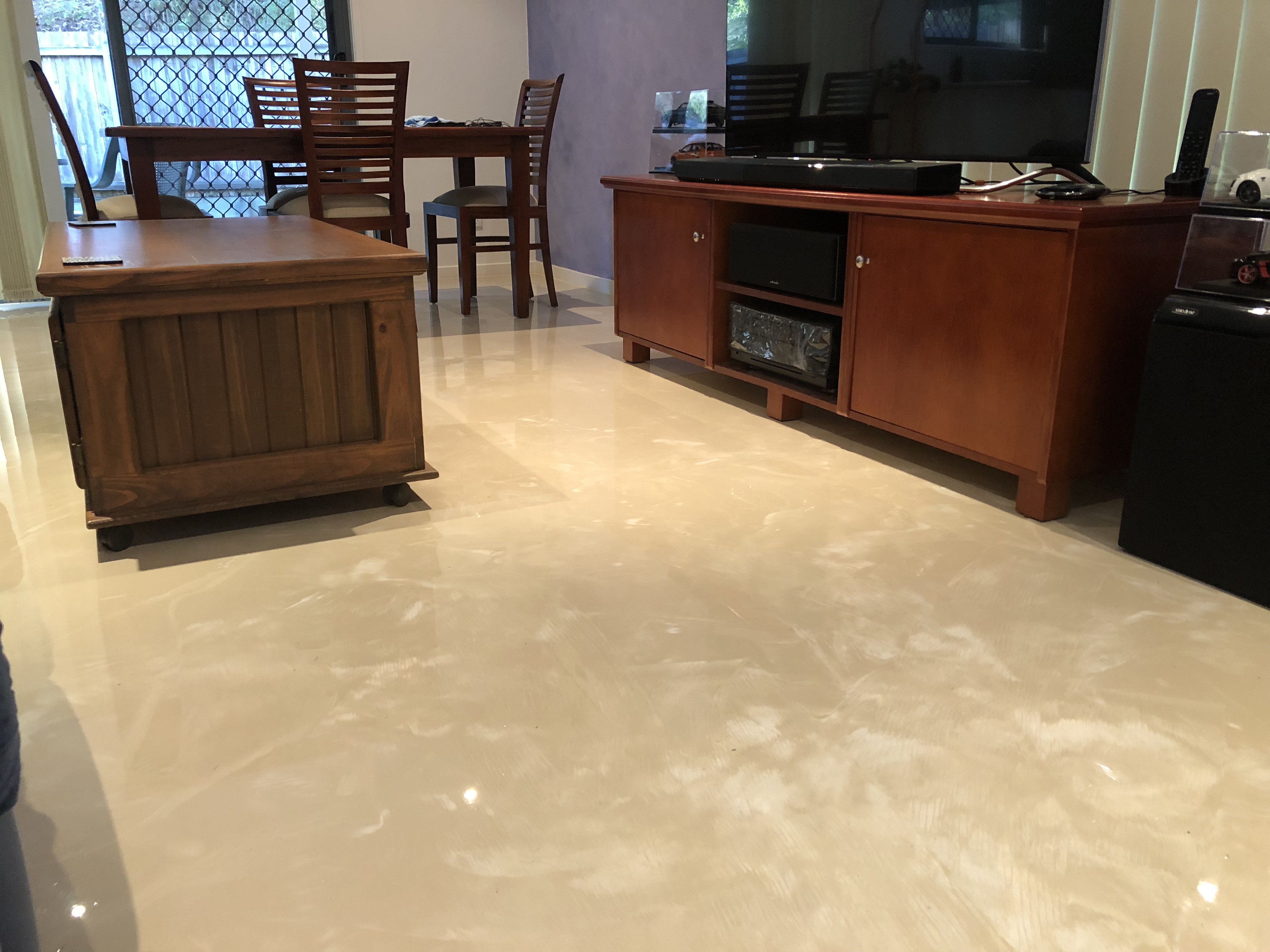 A metallic interior epoxy floor in a living room with beautiful wooden furniture on top.