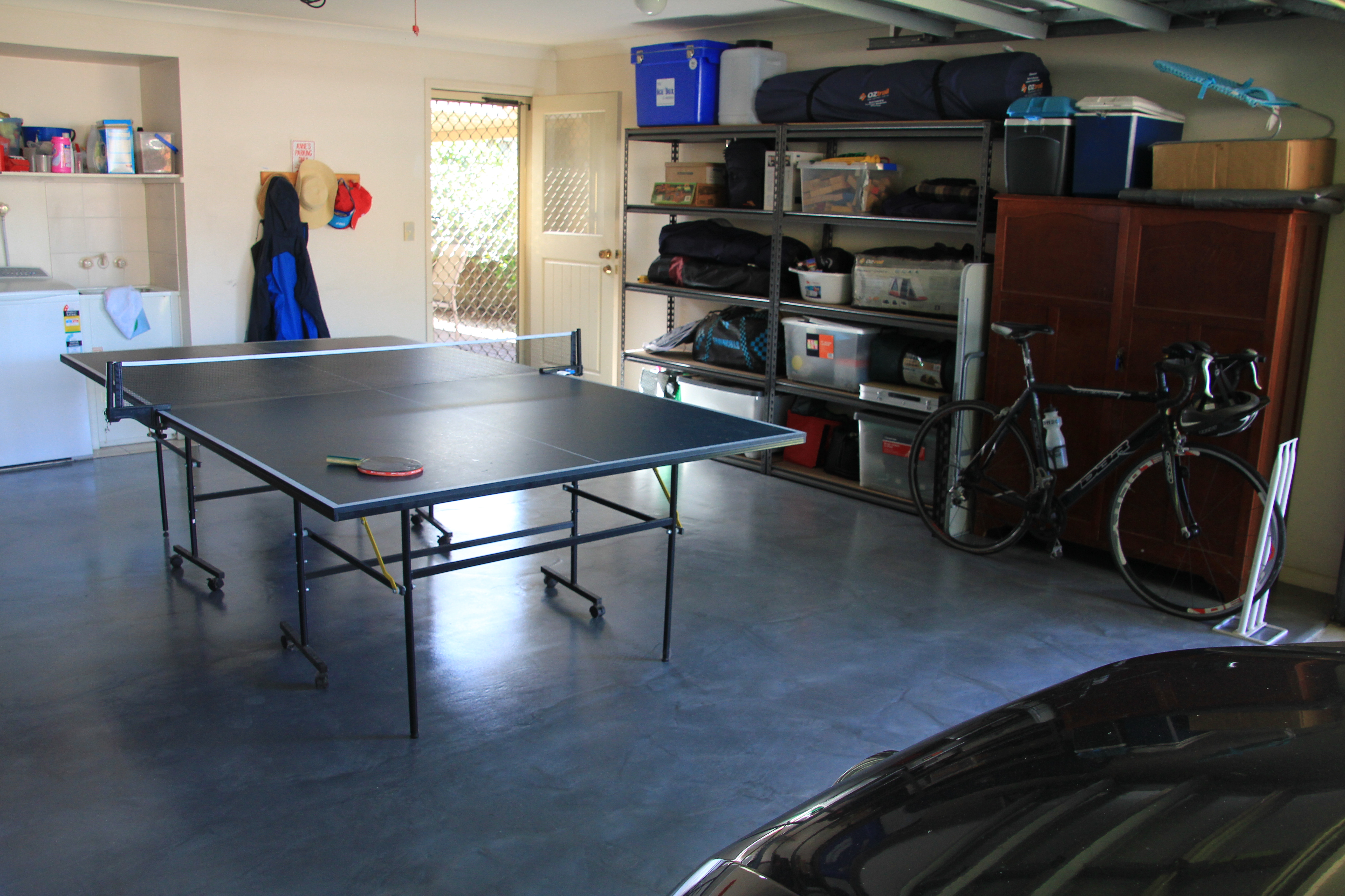 A table tennis set sitting on top of a metallic interior epoxy floor in a garage.
