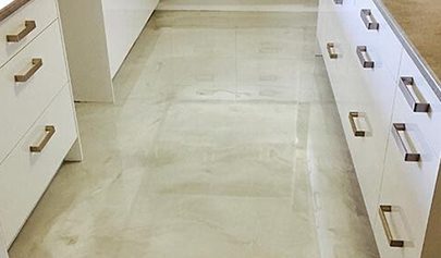 A close up of a high-gloss Oyster Resin Marble finish in a residential kitchen with the reflection of cupboards and ceiling visible.