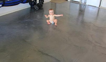 A baby sitting on top of a grey Resin Marble system installed in a residential garage.