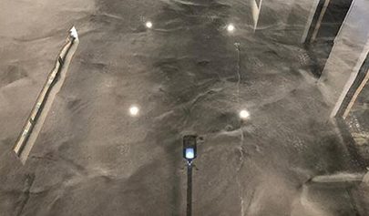A close up of a high-gloss Basalt Resin Marble finish with the reflection of the ceiling and lights visible.