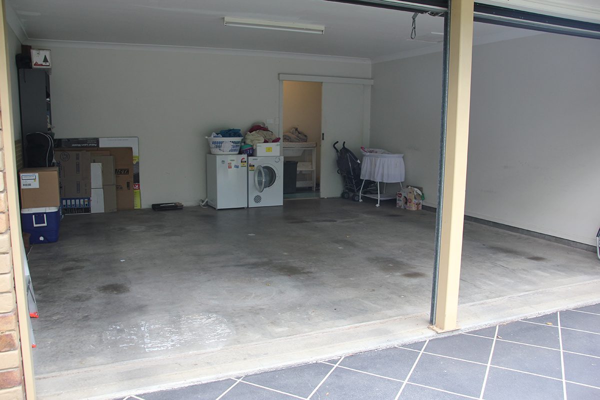 A photo taken before the project from the front of the residential garage with the original, oil-stained concrete slab visible.